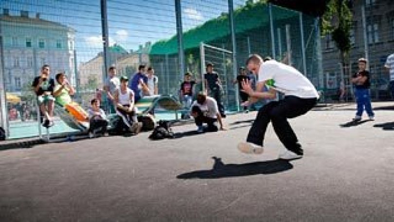 Tanzender Jugendlicher mit jugendlichem Publikum in Ballspielkäfig