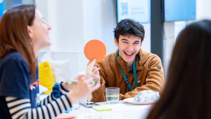 Jugendliche diskutieren und arbeiten gemeinsam an einem Tisch bei einer Veranstaltung