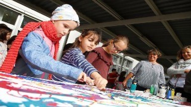 Kinder bemalen mit bunten Farben ein Plakat