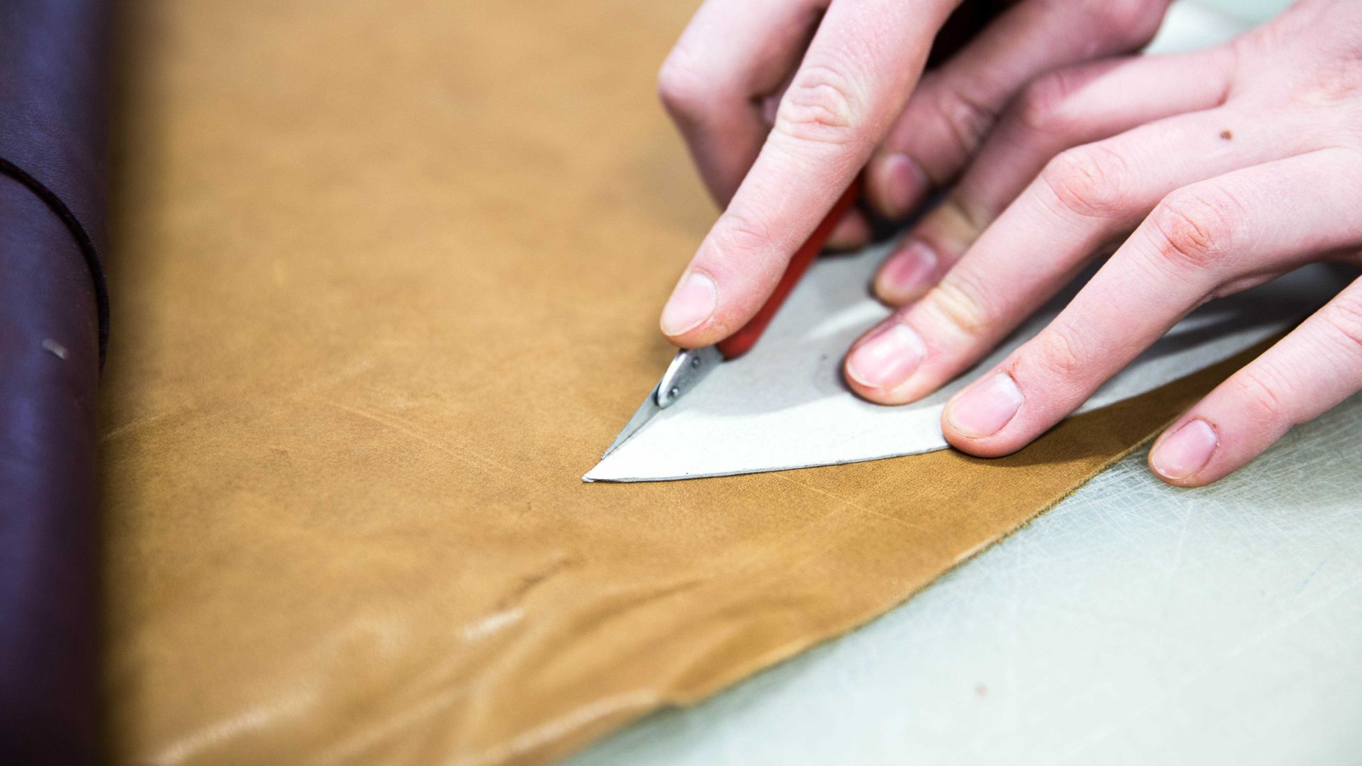 Schülerin schneidet Leder mithilfe einer Schablone aus