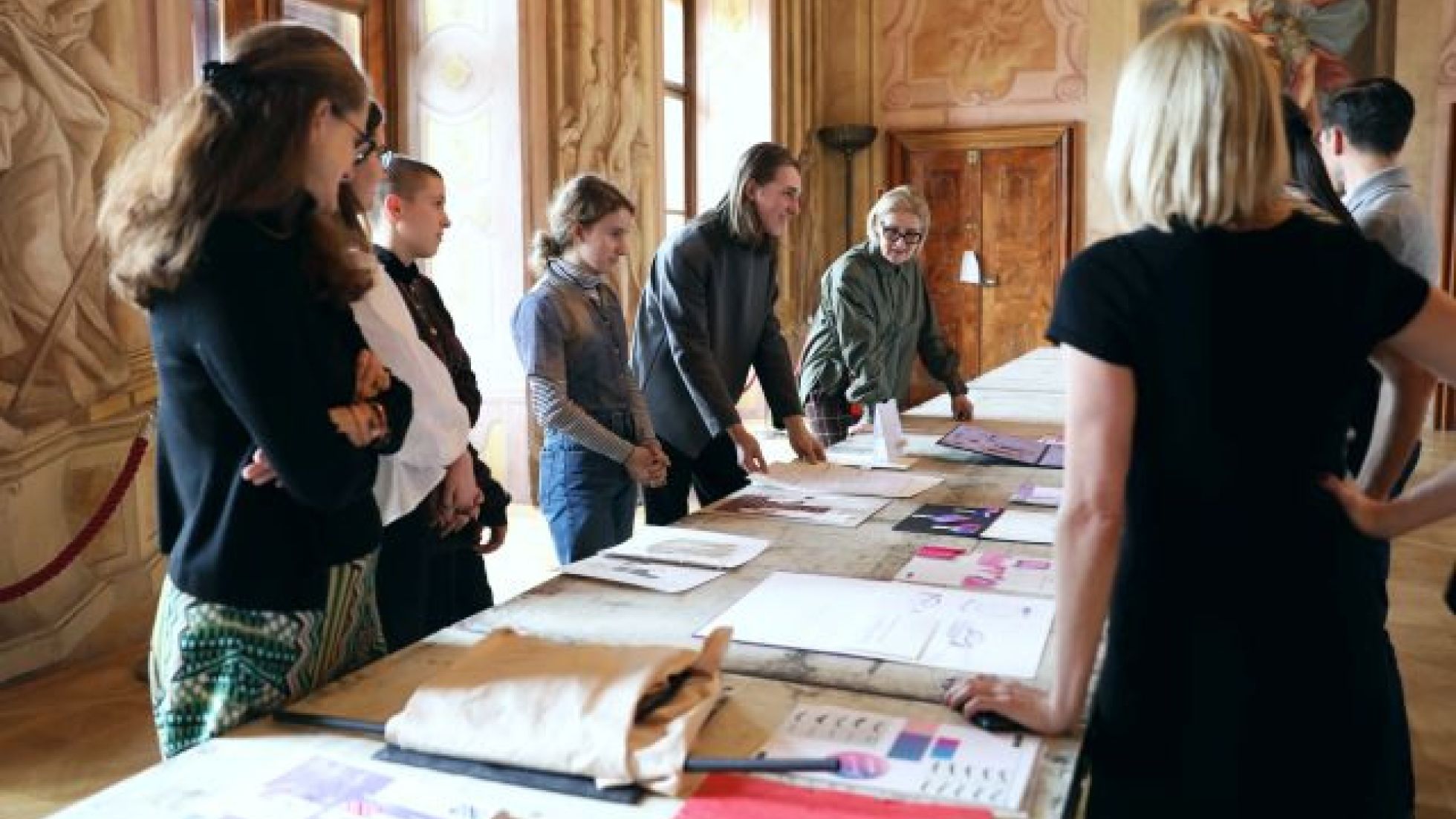 copyright: Modeschule Hetzendorf / Michaela Zimmermann Mehrere Personen stehen um einen Tisch mit Entwürfen