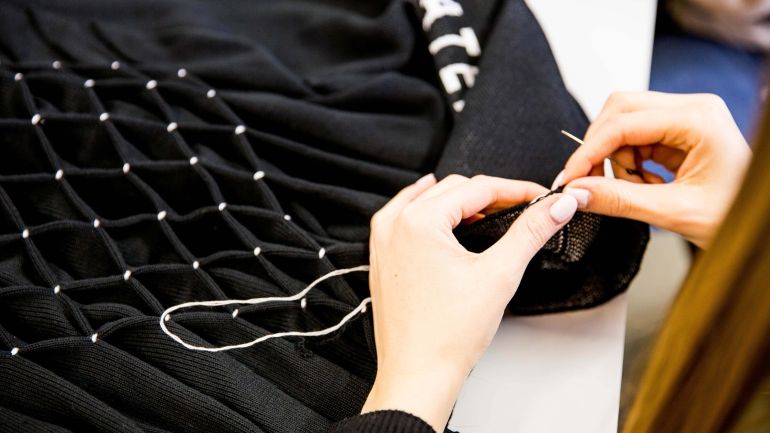 copyright: Paul Mittnik Schülerin arbeitet an einem Kleidungsstück aus Strickstoff