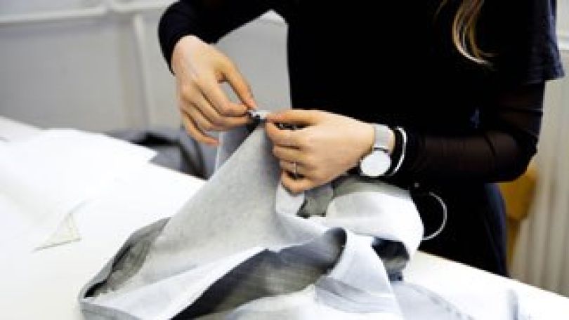 Schülerin heftet Kleidungsstück