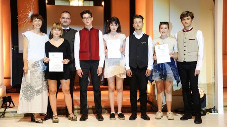 Mehrere Personen stehen nebeneinander, drei junge Frauen halten Urkunden