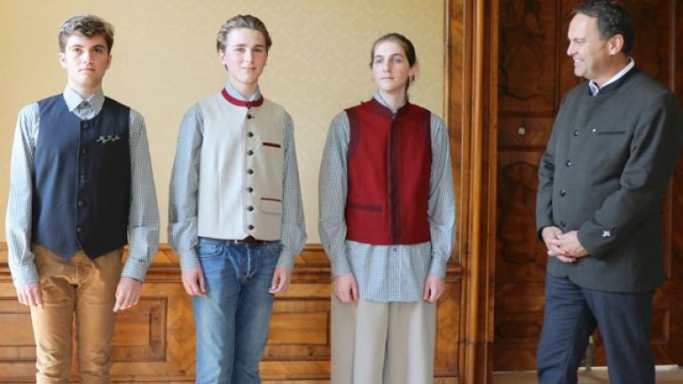 Zwei junge Männer, eine junge Frau und ein Herr nebeneinander in Tracht