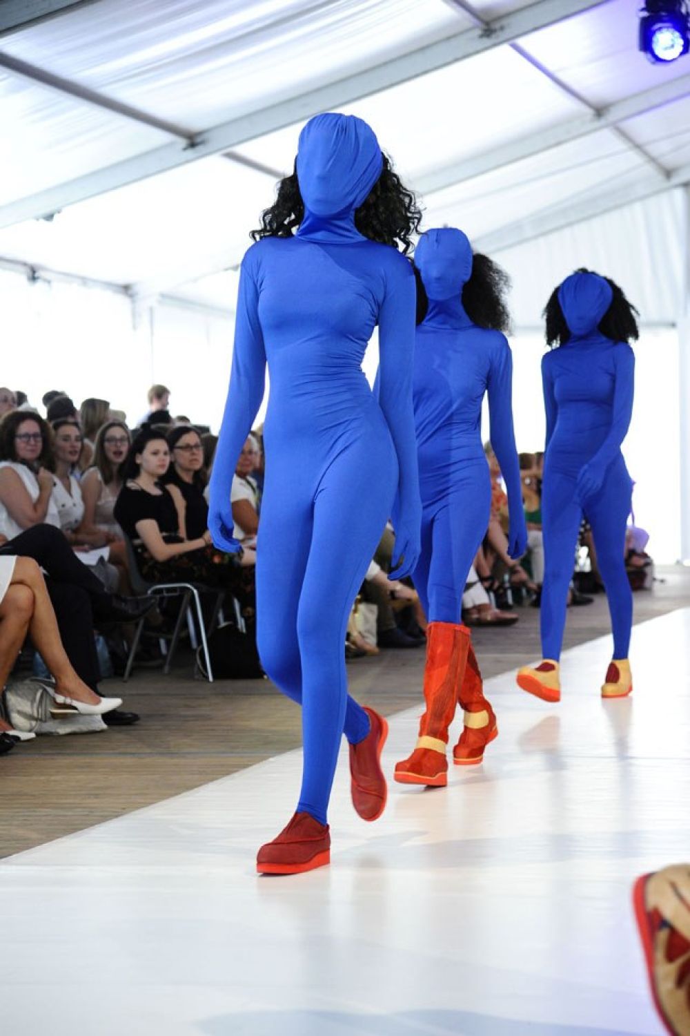 Modeschülerinnen in blauem engen Anzug, der auch das Gesicht bedeckt