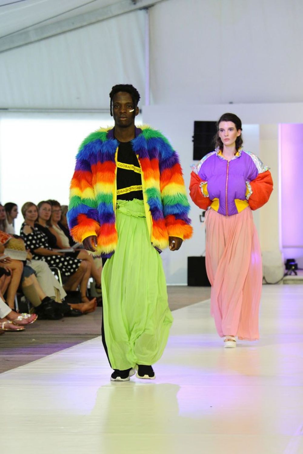 Modeschüler mit schriller, bunter Kleidung als Model auf dem Laufsteg