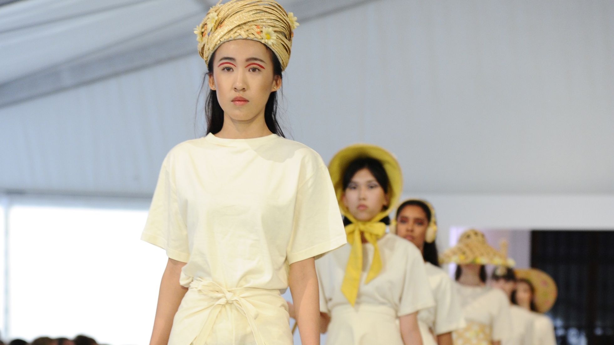 Schülerinnen präsentieren Hüte auf dem Laufsteg