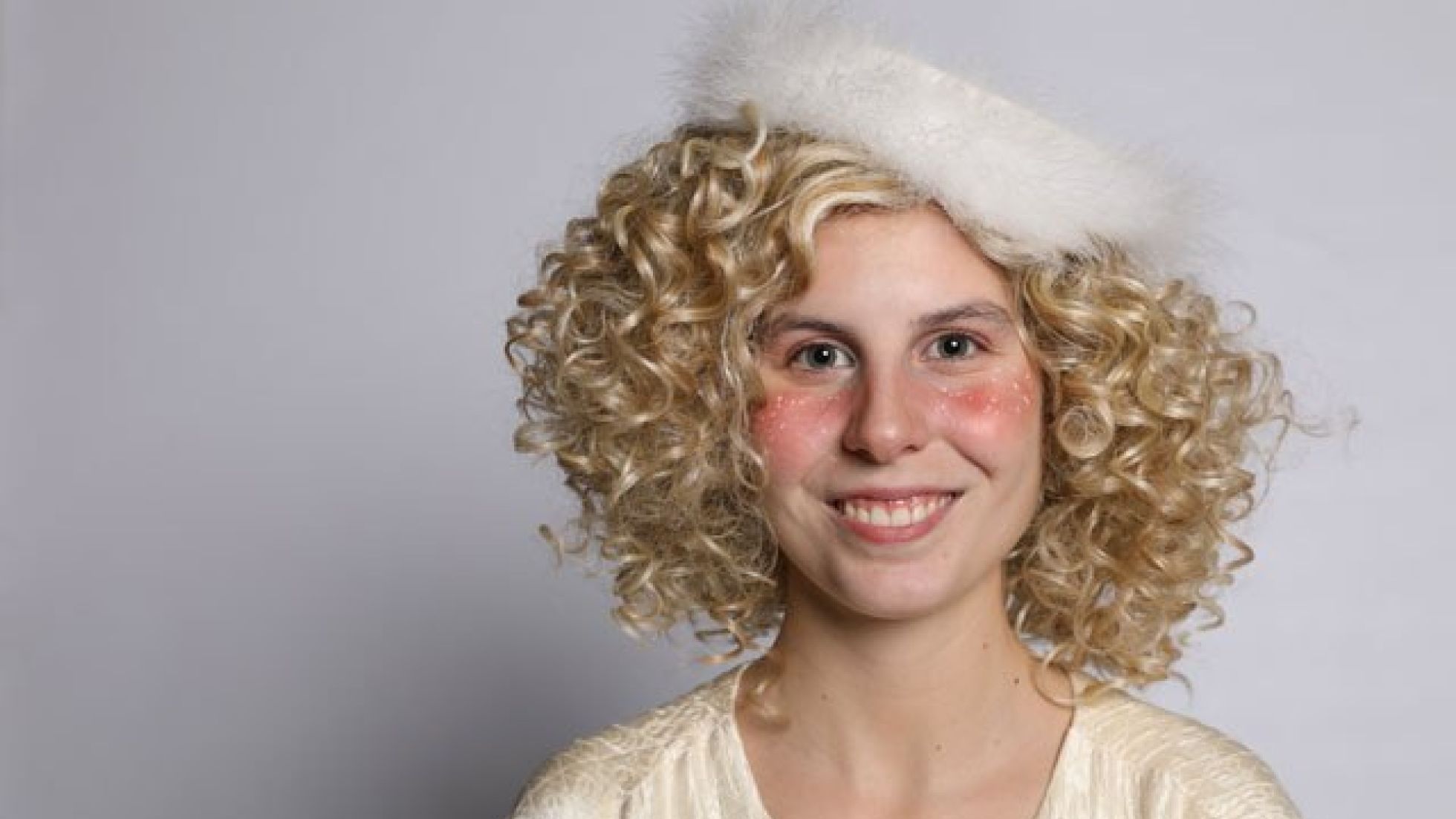 Frau mit goldenen Locken, weißem Umhang und weißem Hut