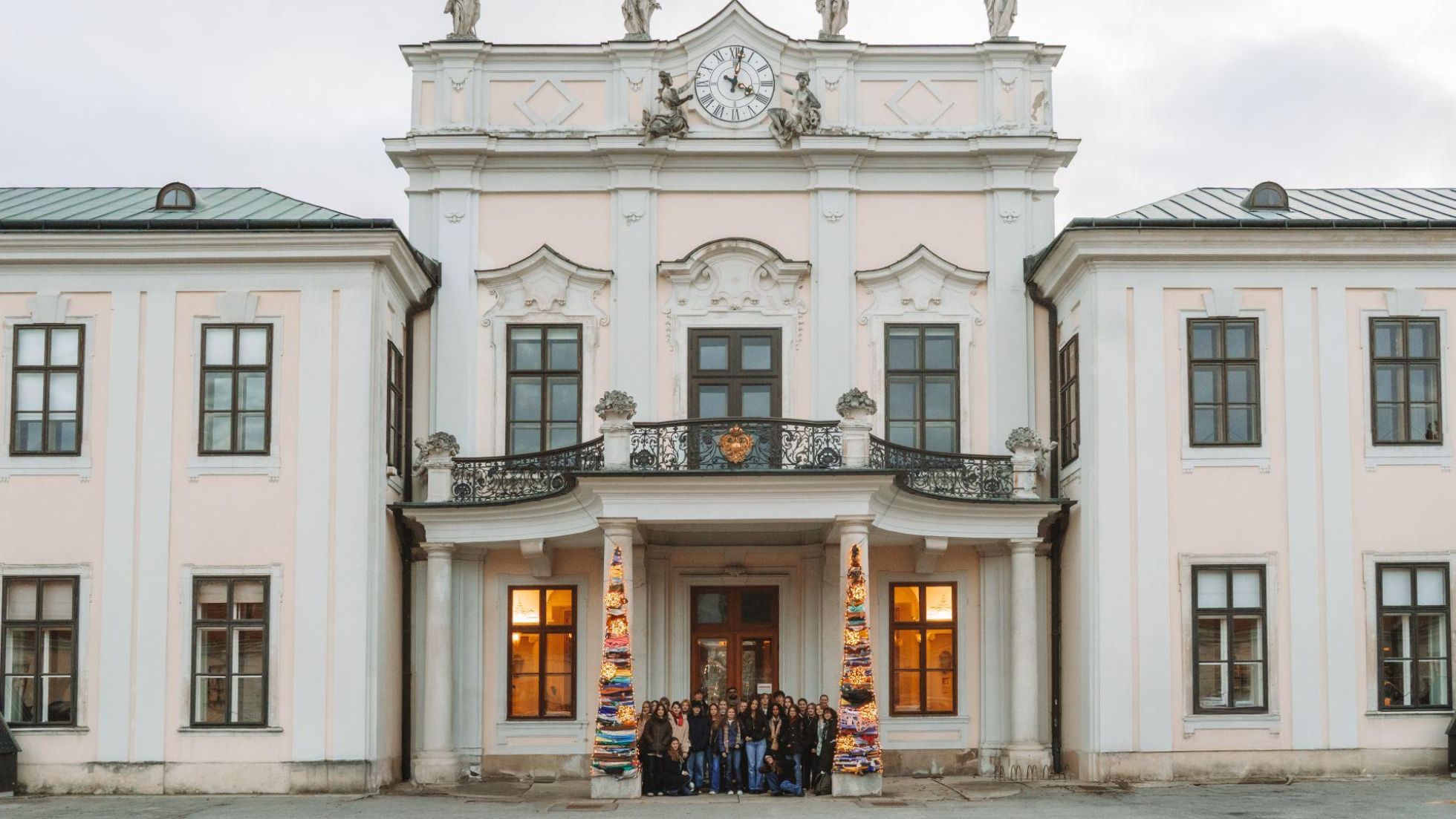 Bunte Weihnachtsbäume vor dem Schloss neben einer verglasten Holztür