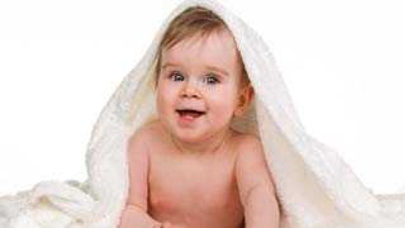 ein Baby lächelt unter eine Babydecke