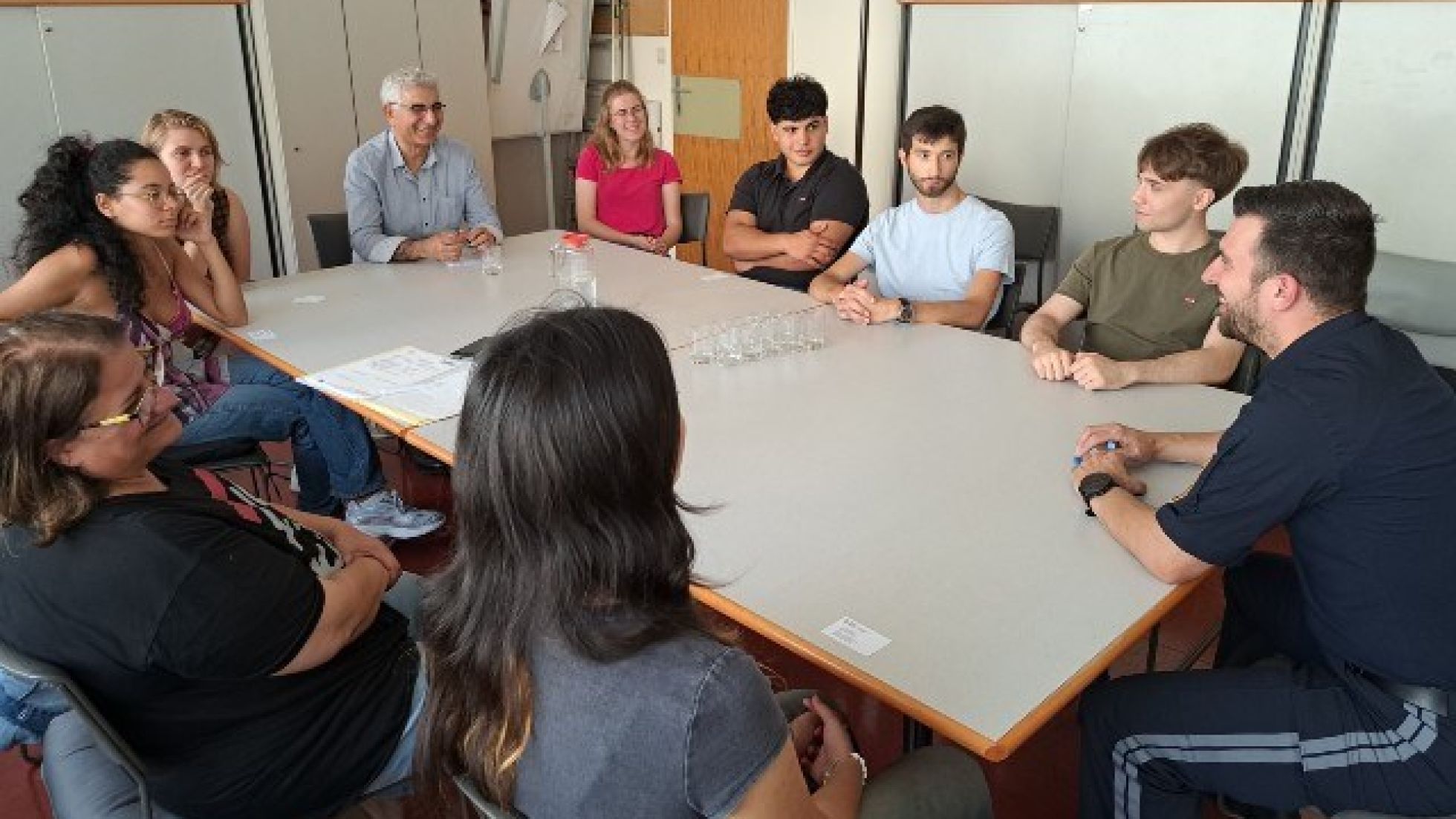 Mehrere Menschen sitzen an einem Tisch mit einem Polizist
