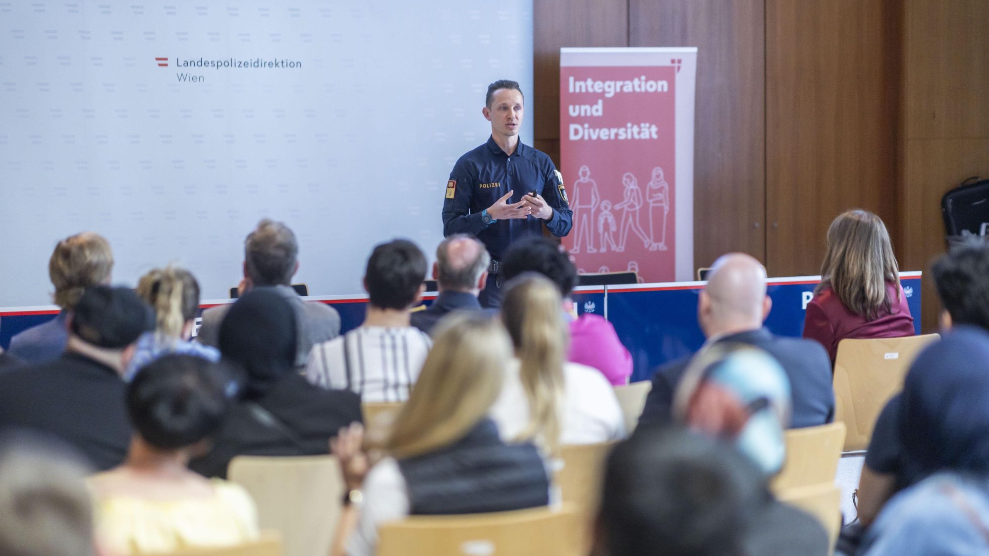 Polizist hält Vortrag vor einer Gruppe an Menschen