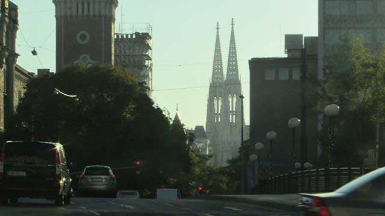 copyright: ARGE BWM Tabor Feller auf einer mehrspurigen Straße, in Blickrichtung im Hintergrund eine Kirche, rechts erst Geländer, dann Gebäude, links Türme eines Gebäudes