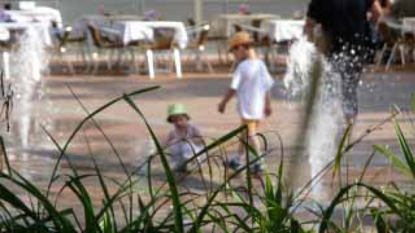 Kinder spielen mit dem Wasserspiel auf einem urbanen Platz im Sommer