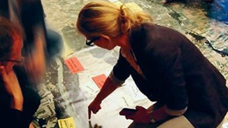 Eine Frau weist auf einen bestimmten Punkt auf einem Plan hin.