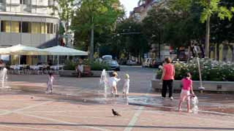Platz mit Wasserspielen und spielenden Kindern im Sommer