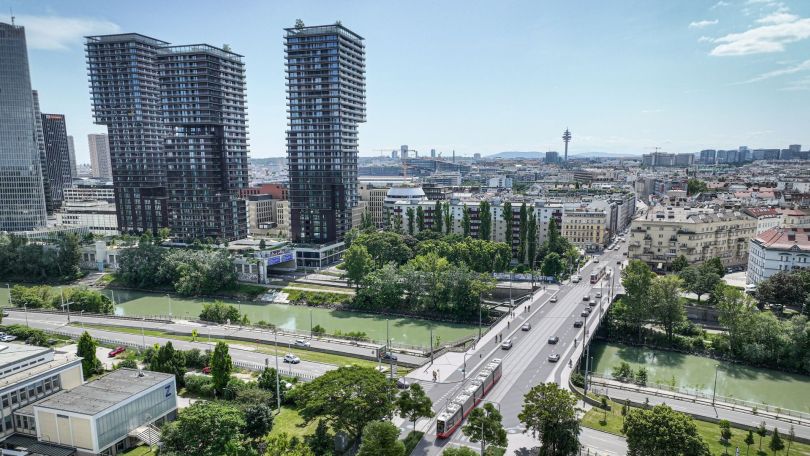 Visualisierung einer breiten Brücke mit Pkw und Straßenbahn, dahinter Stadtgebiet inklusive Skyline