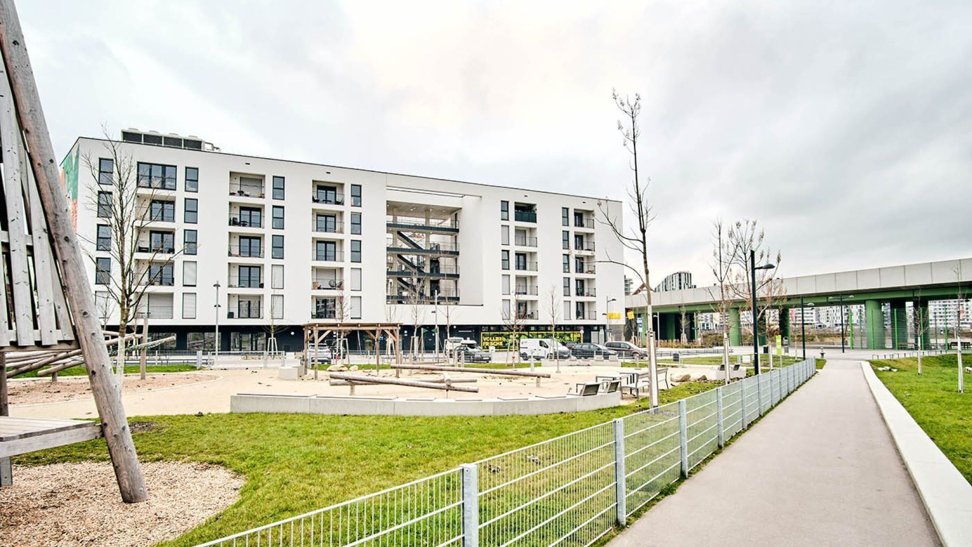 Mehrstöckiges Gebäude mit eingezäuntem Spielplatz davor