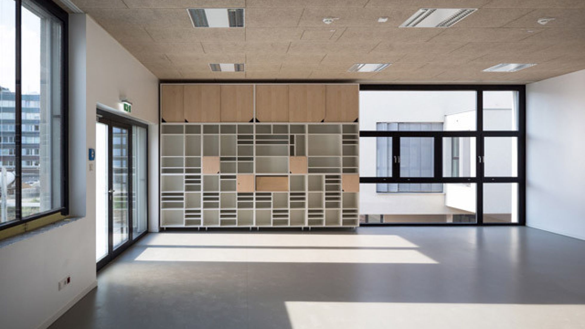 copyright: pierer.net Innenansicht eines Bildungsraumes. An der Stirnseite befindet sich neben der geschosshohen Verglasung eine offene ebenfalls raumhohe Schrankkonstruktion.