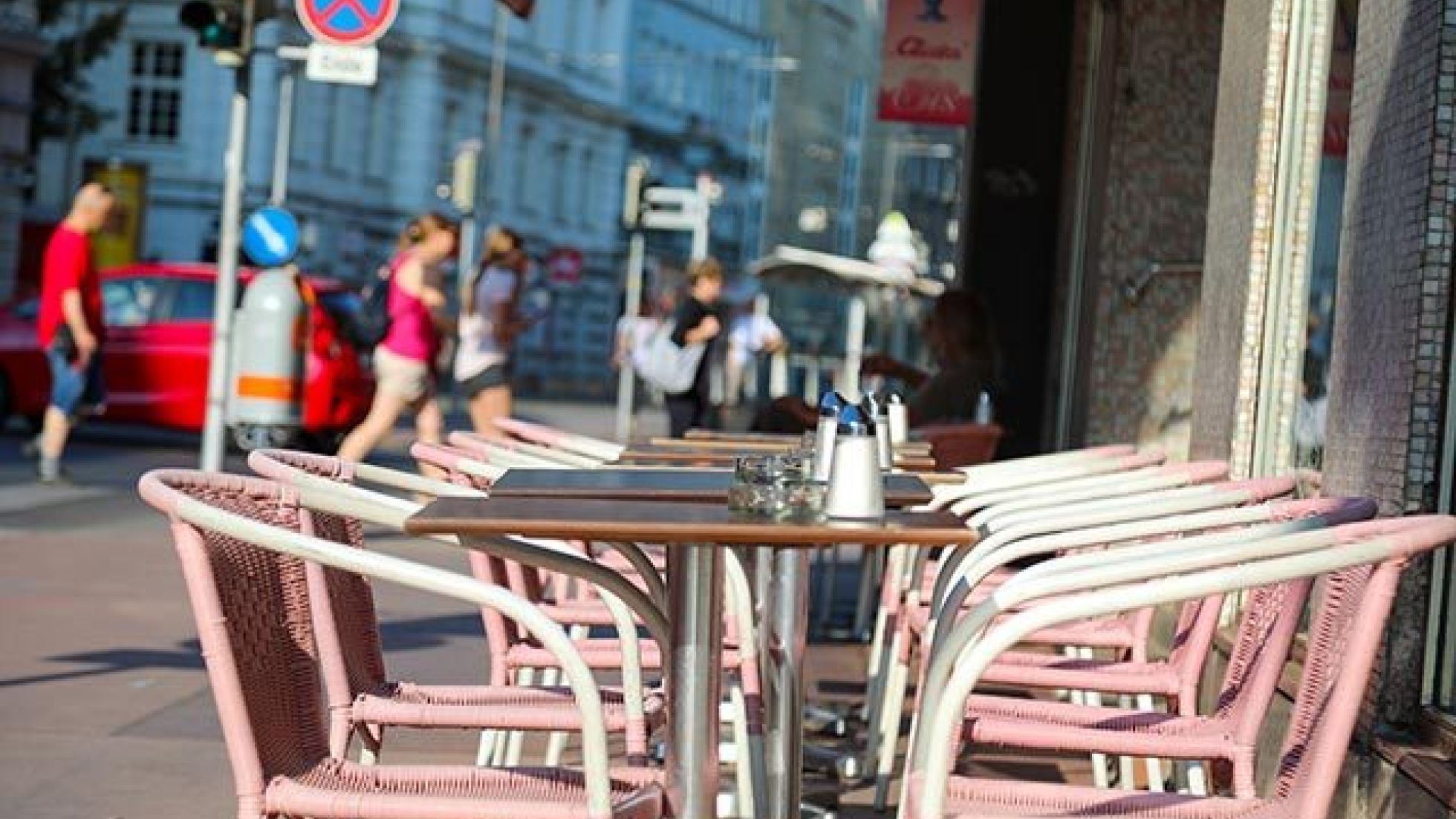 Sessel und Kaffeehaustische auf einem Gehsteig.