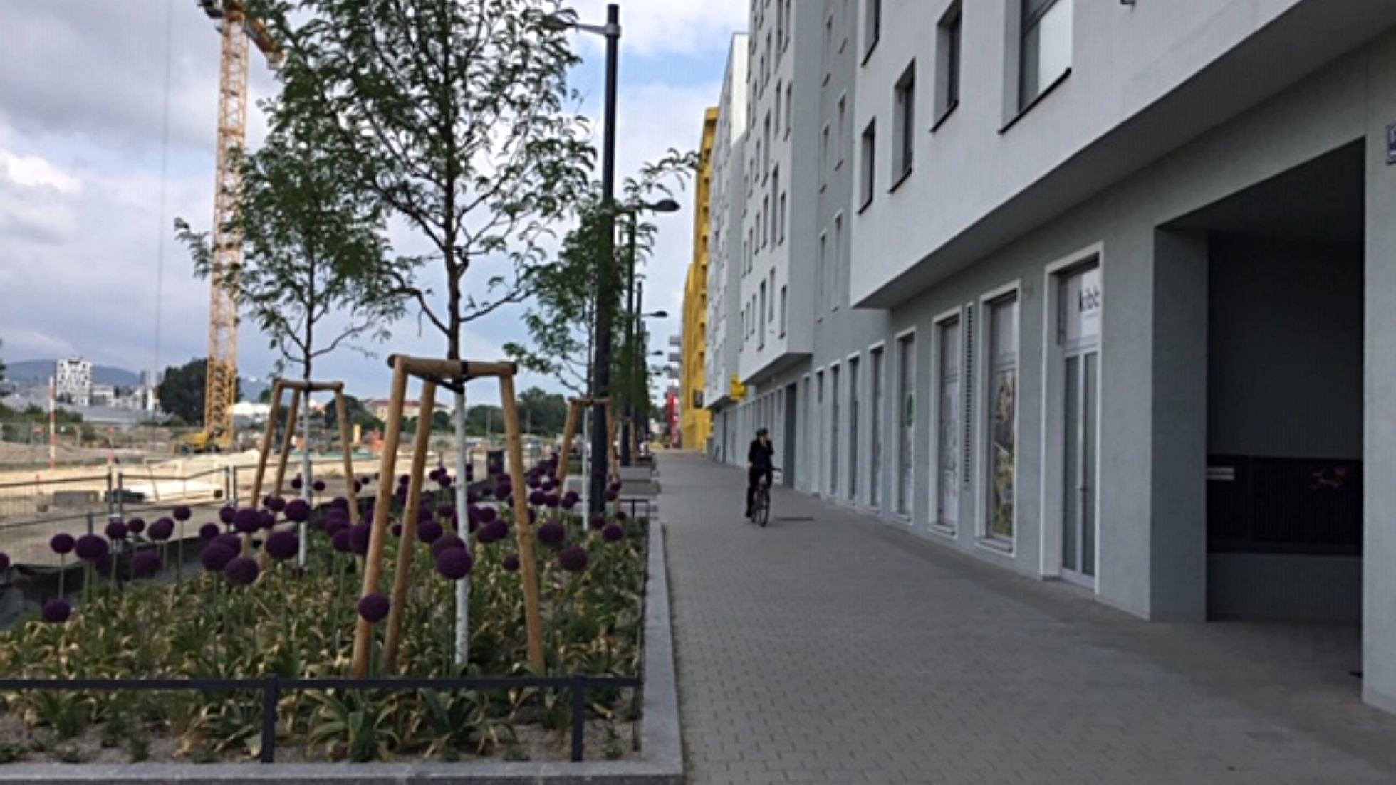 Wohngebäude, daneben Gehweg und Sitzmöglichkeiten