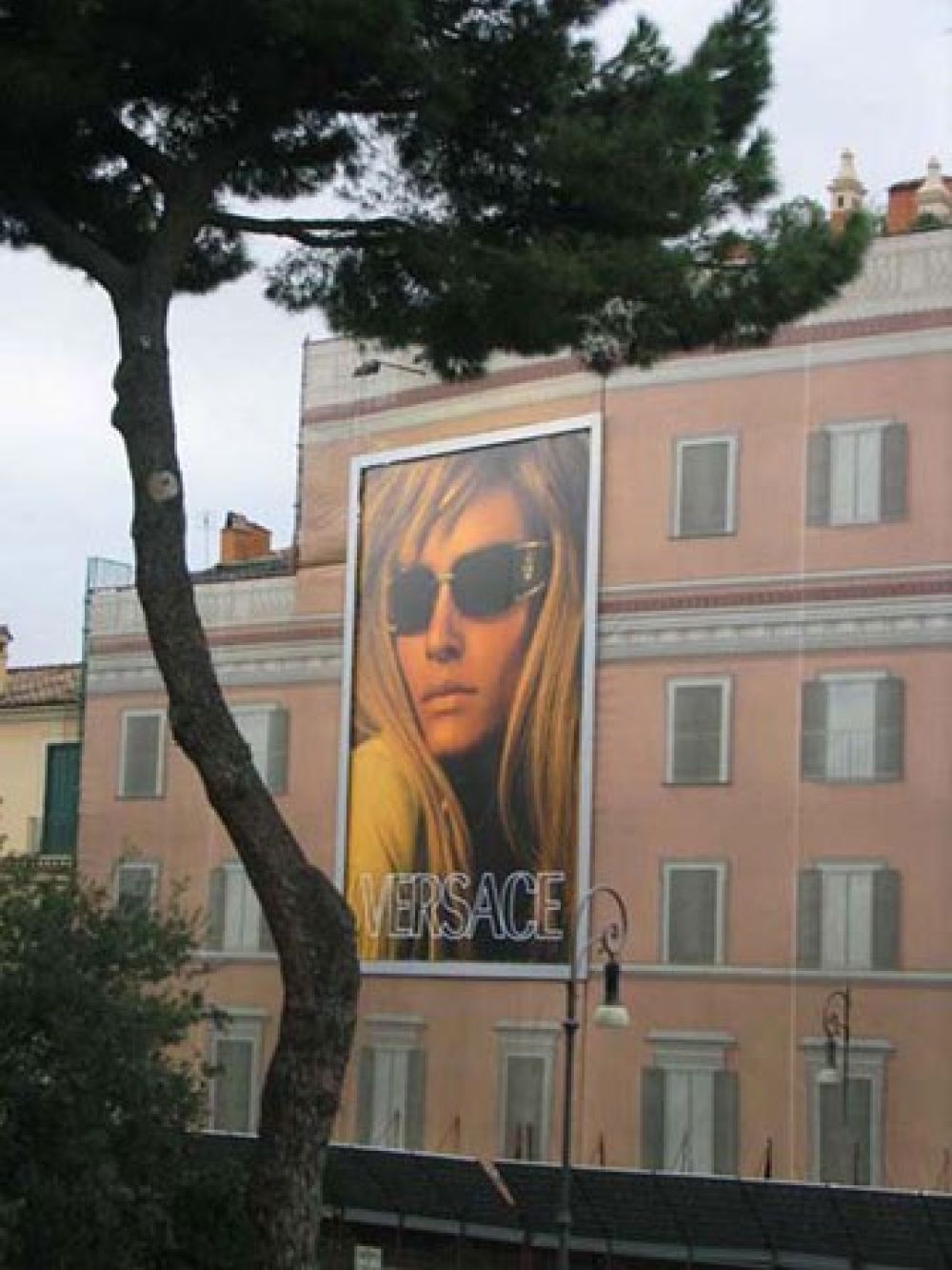 <p>Werbung auf Staubnetzen</p> Haus mit Transparent verkleidet, das im Hintergrund eine gemalte Fassade zeigt und darauf ein Werbesujet beinhaltet