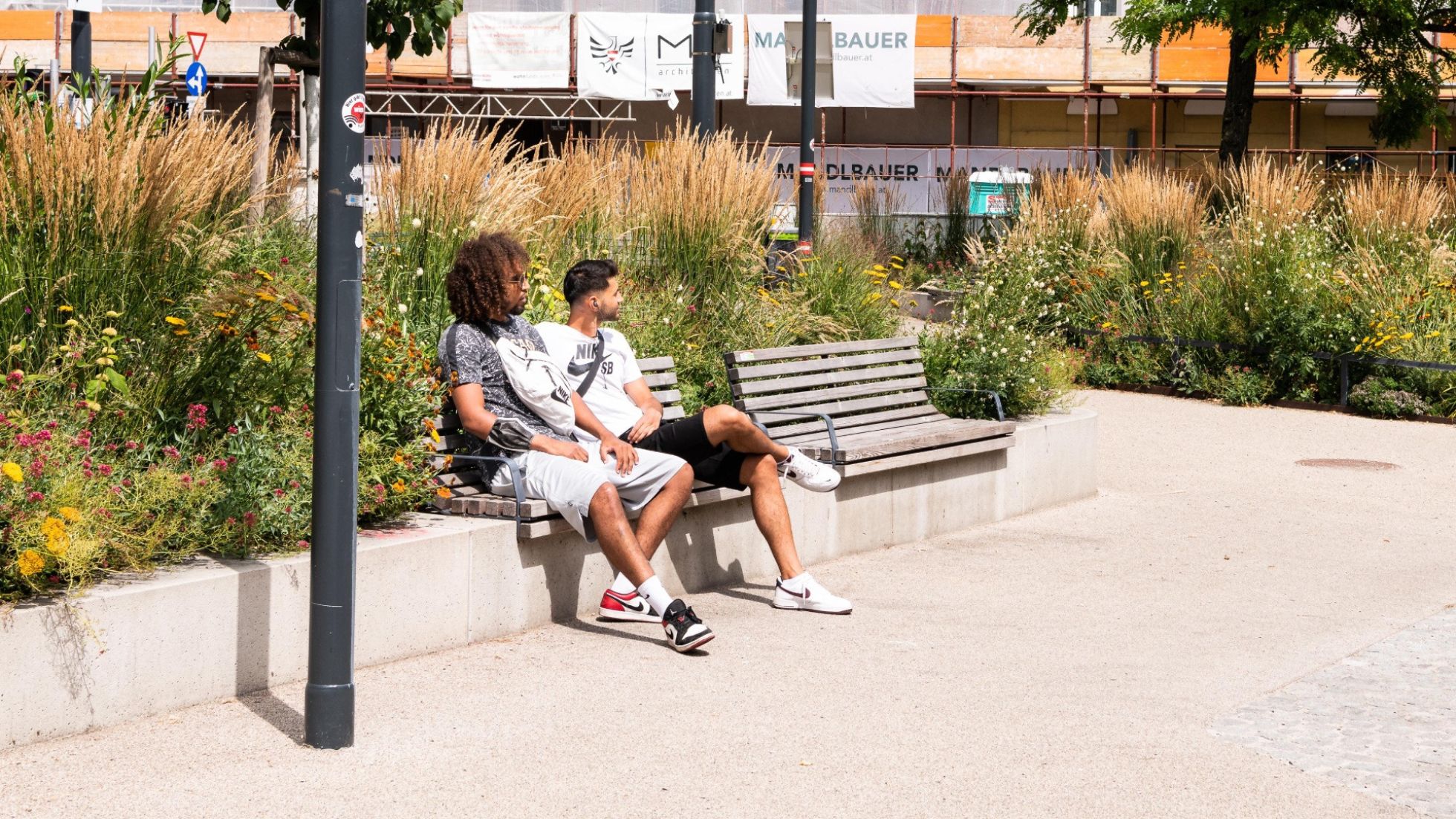 copyright: Stadt Wien / Johannes Wiedl 2 Menschen sitzen auf einem Platz am Rand einer Grünfläche