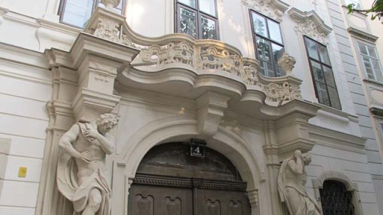 Ausschnitt einer Hausfassade, Geschwungener steinerner Balkon über dem barocken Eingangsportal, Sicht von unten