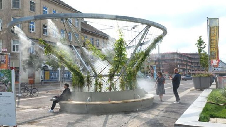 Großen Rundbank unter begrüntem Rankgerüst und kühlendem Sprühnebel