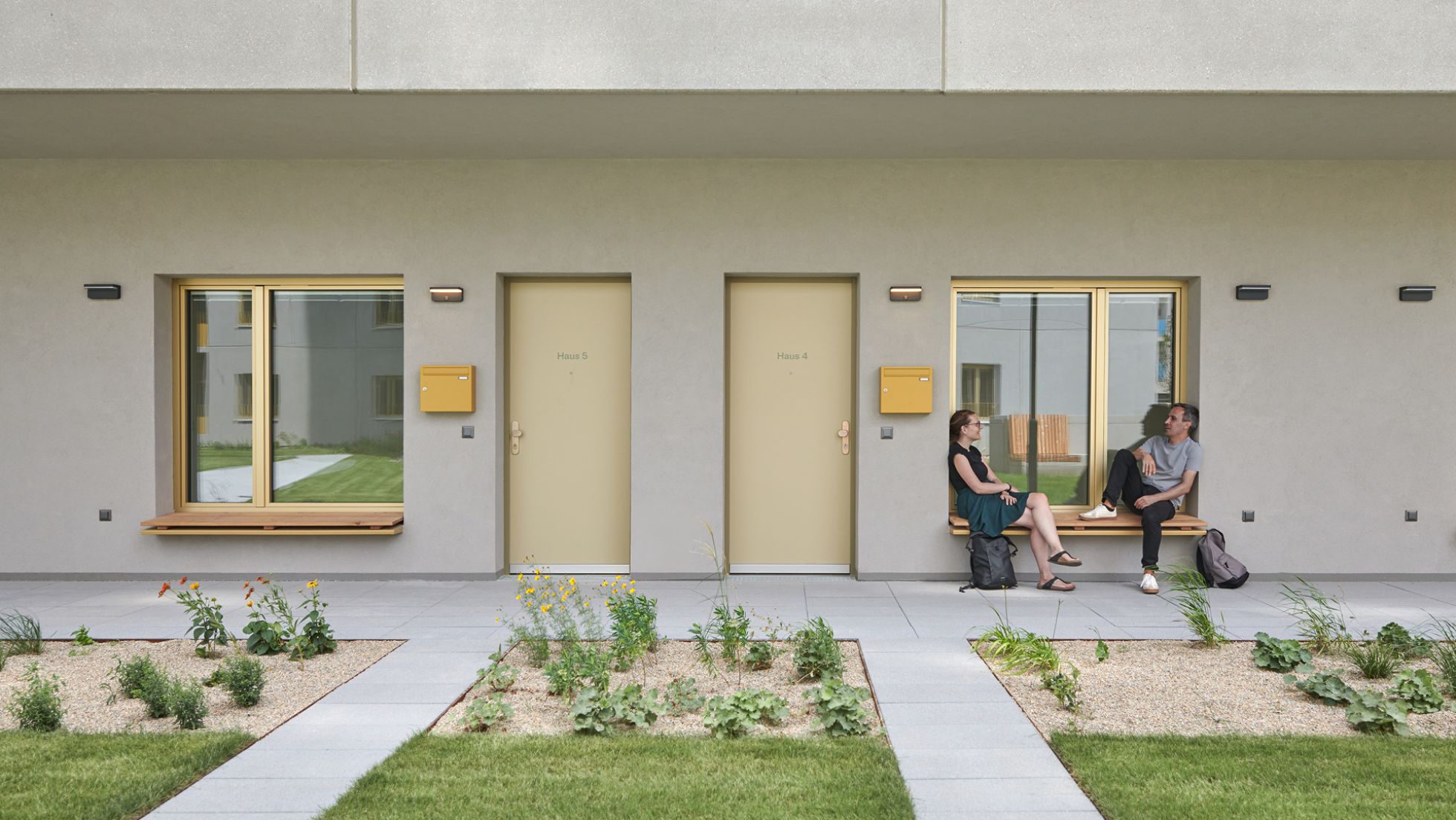 copyright: Andreas Buchberger Wohnungsfronten mit Türen und Fenster, 2 Menschen sitzen auf einer Fensterbank