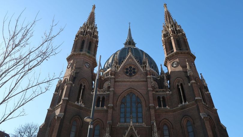 Fassade einer Kirche mit Kuppeldach und Spitze sowie 2 Türmen.