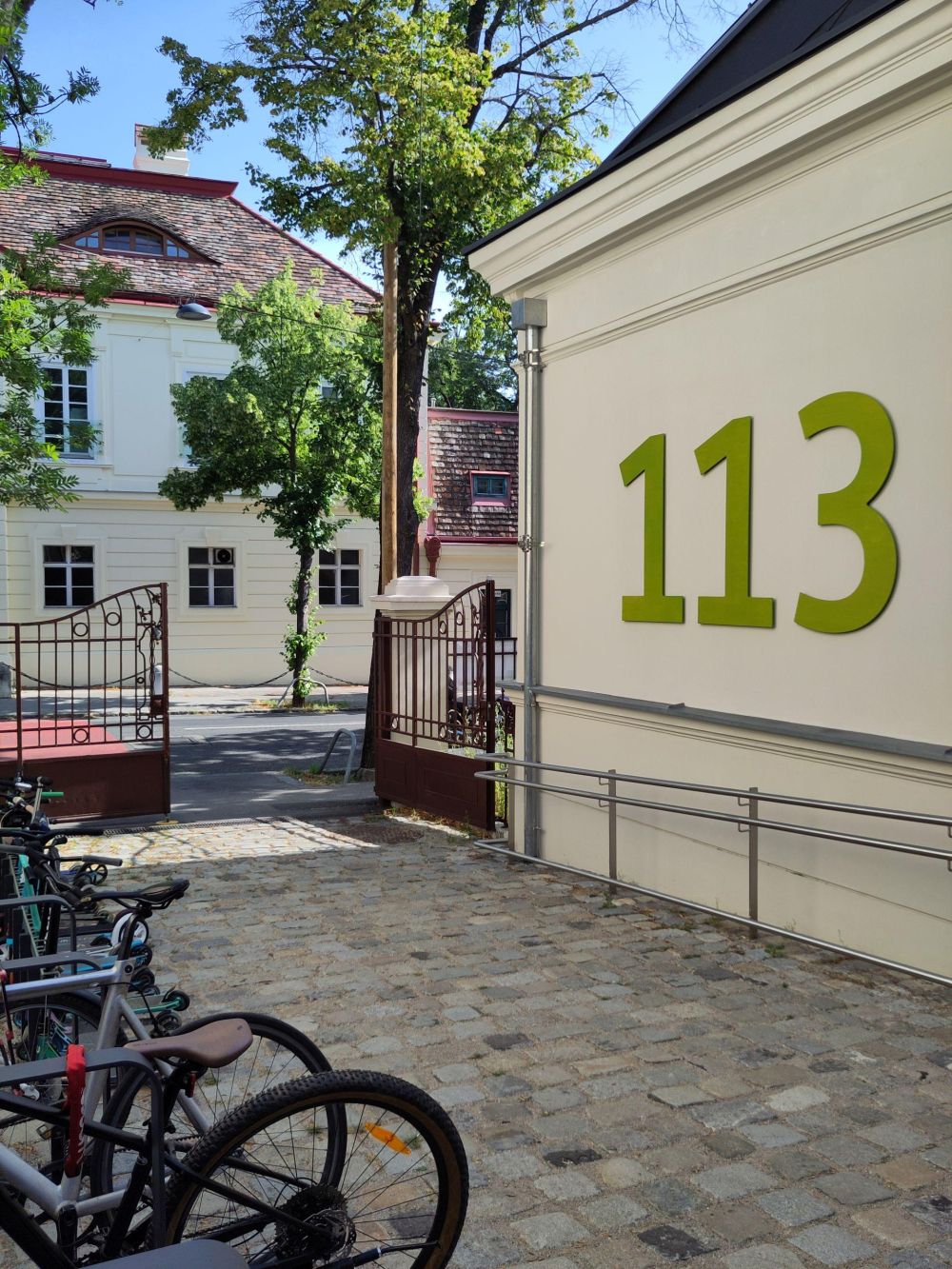 Eingangsbereich einer Schule mit großem Metalltor und Fahrradständer.