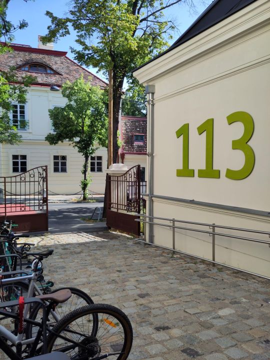 copyright: UIV Urban Innovation Vienna Eingangsbereich einer Schule mit großem Metalltor und Fahrradständer.