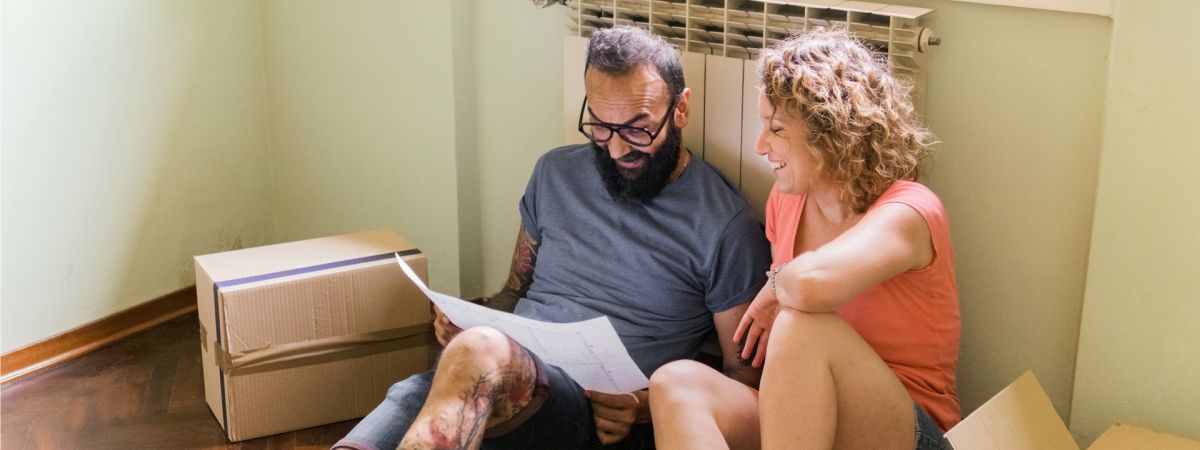 Ein Mann und eine Frau sitzen auf dem Boden vor einem Heizkörper.