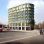 Rendering Wohnhaus mit begrünter Fassade, davor Platz mit Bushaltestellen