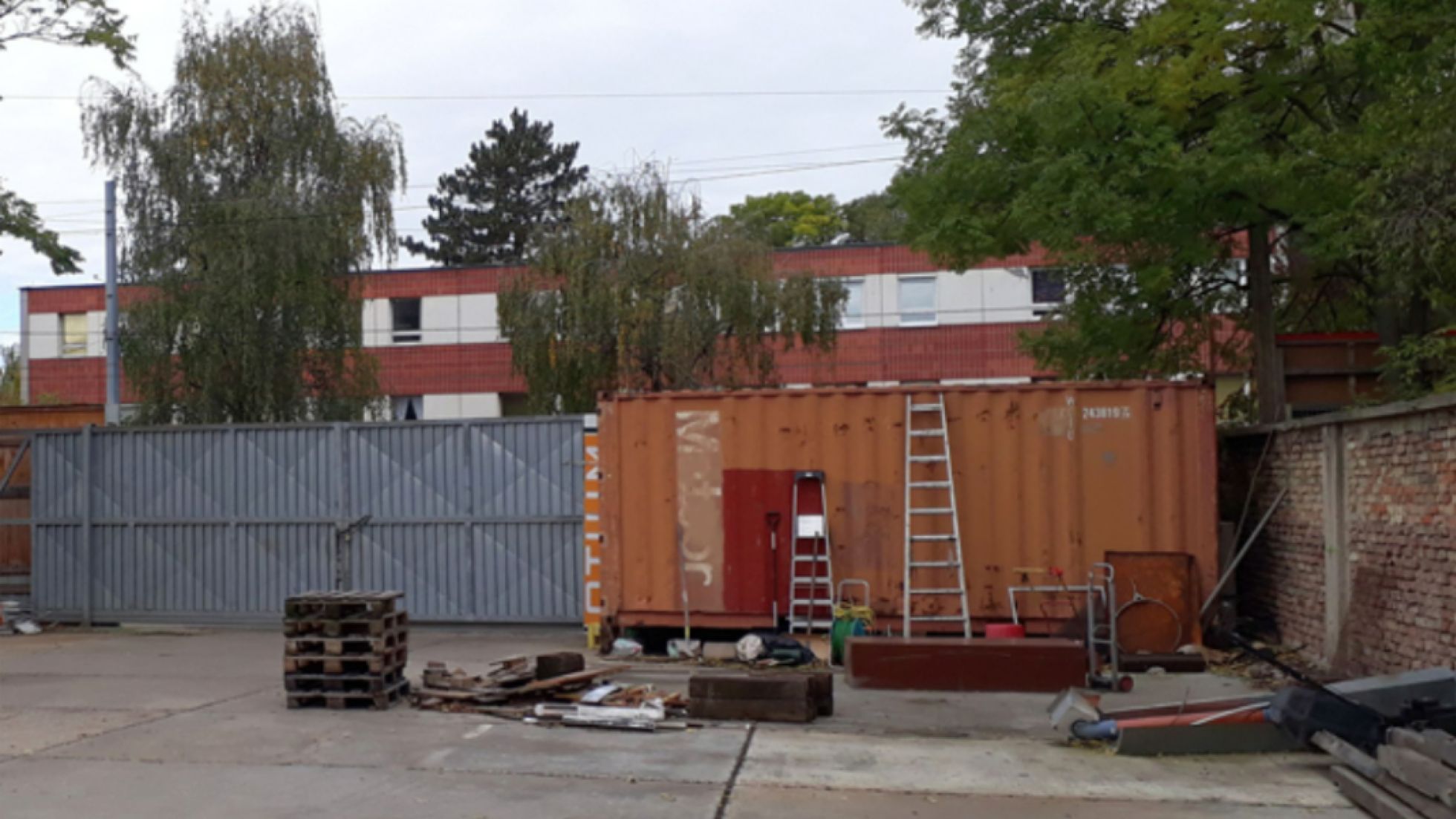 Betonfläche, Container, Leitern, Holzpaletten