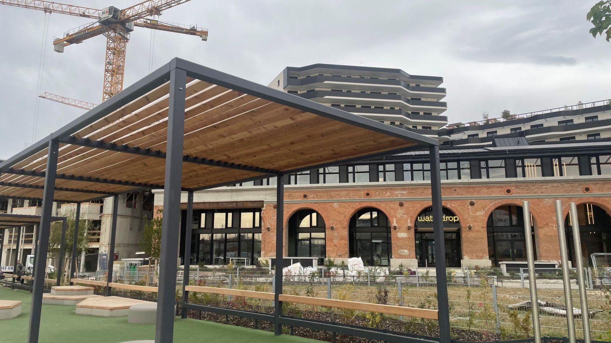 copyright: Stadt Wien Aufenthaltsbereich mit Pergola vor einer modernisierten historischen Backsteinhalle