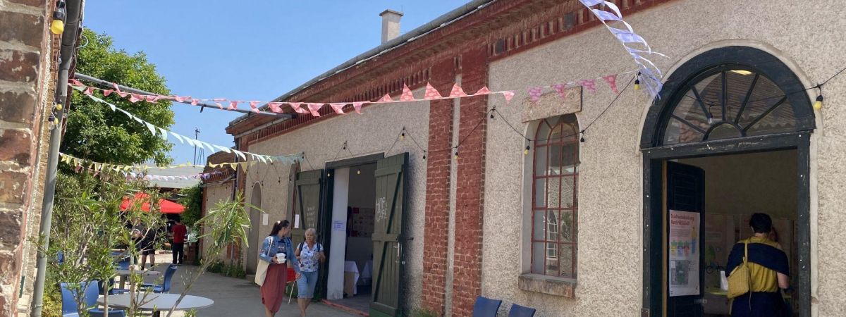 Älteres Gebäude mit Backstein und rundem Türbogen, davor Wimpelketten