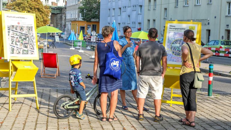 Menschen stehen vor Schautafeln im Freien