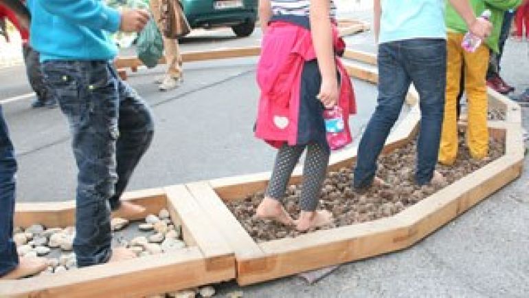 Kinder gehen auf einem Barfuß-Parcours