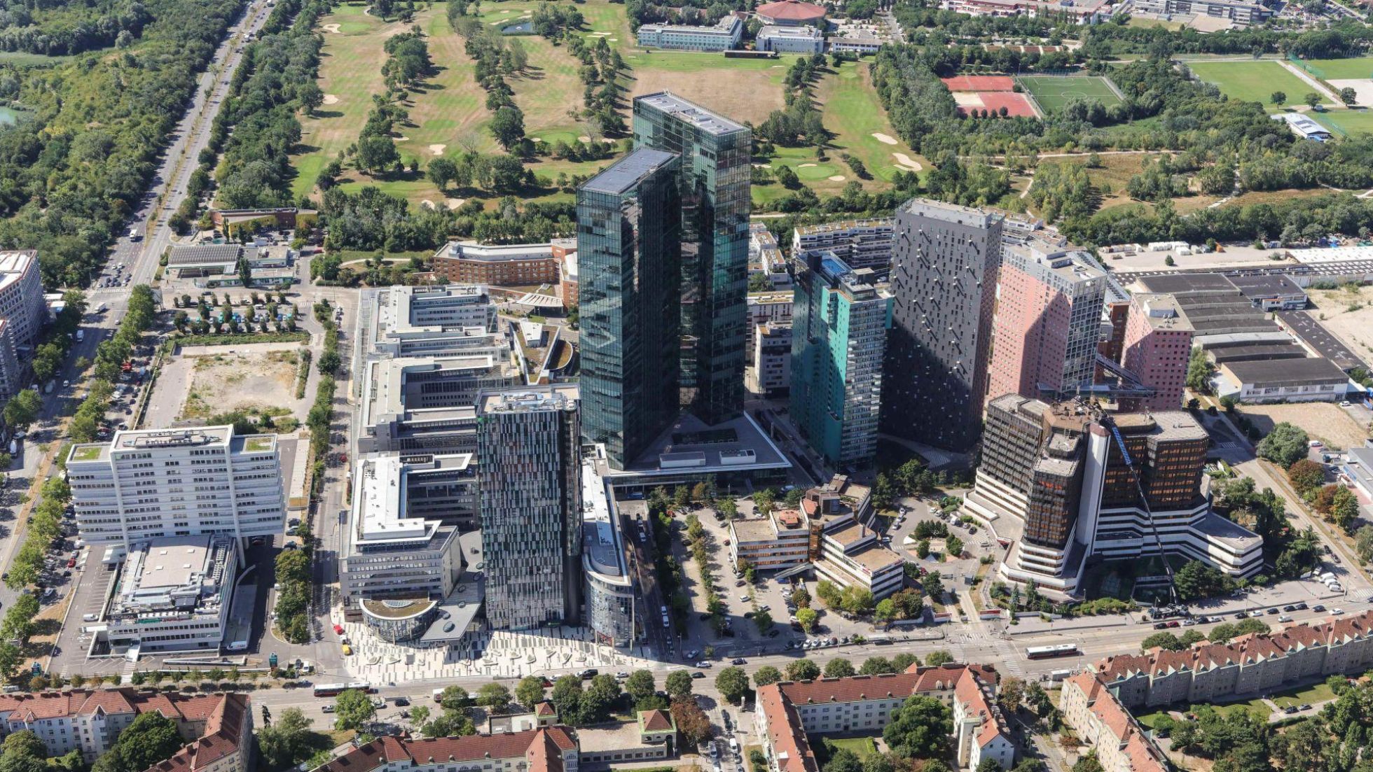copyright: Stadt Wien / Christian Fürthner Mehrere Hochhäuser mit Glasfassade, eine Straße führt rundherum, im Hintergrund sind Bäume und Wiesen