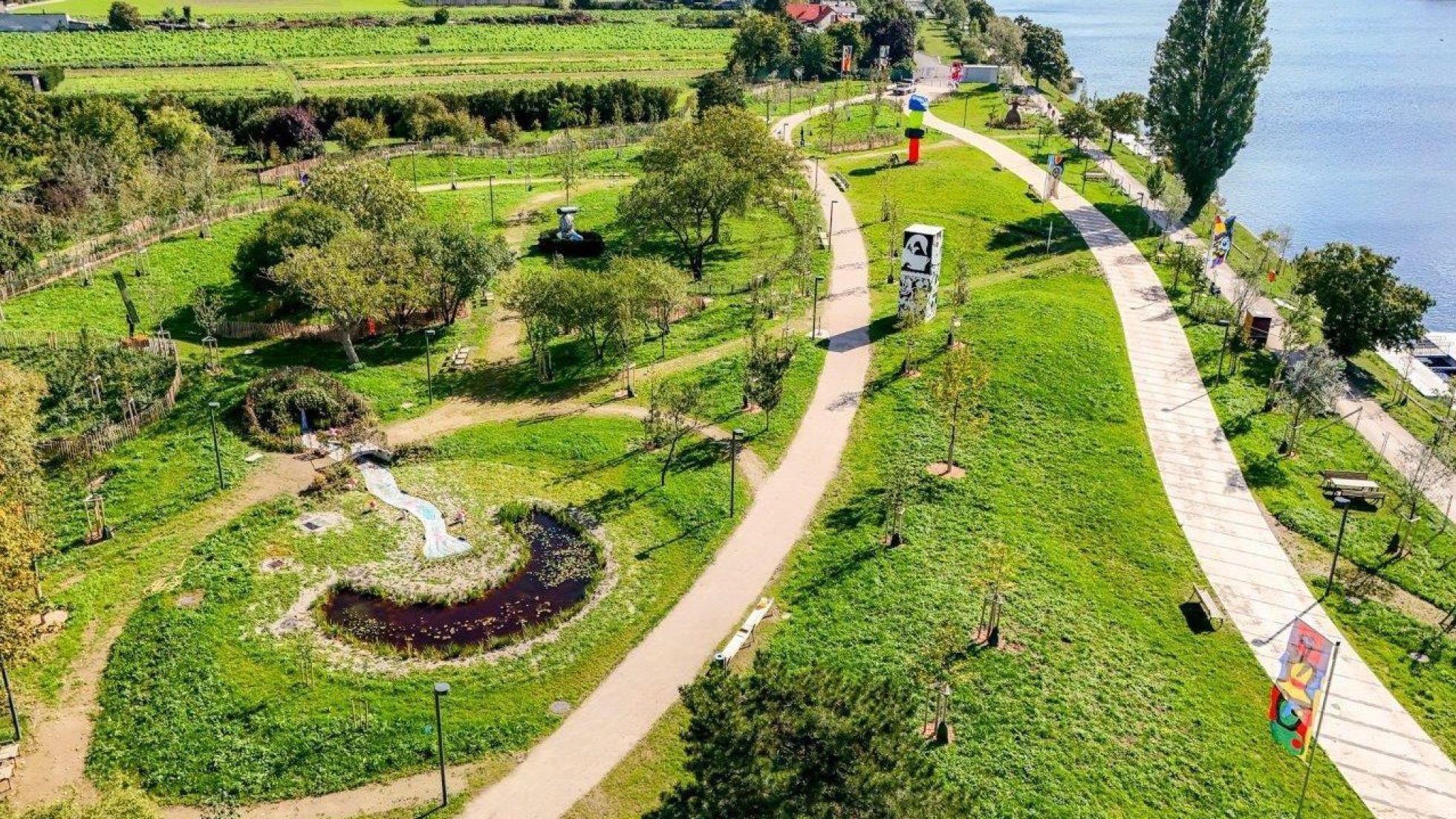 Park mit Wegen, Bäumen, Sitzgelegenheiten am Wasser