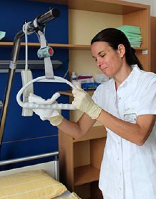 copyright: M. Jaros Eine Frau desinfiziert den Griff zum Aufziehen für Patienten oberhalb eines Krankenbettes