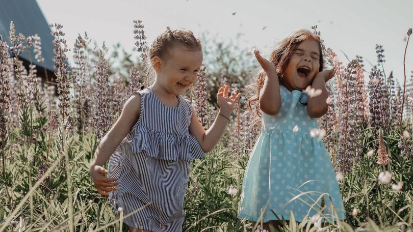 copyright: Pixabay Zwei Mädchen laufen lachend durch hohes Gras und Blüten