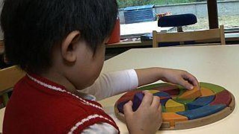 Kind legt Stein in ein Puzzle