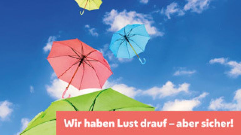 Bunte Regenschirme am Himmel und Text "Wir haben Lust drauf - aber sicher!"