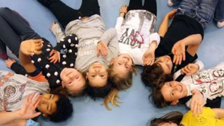 Im Kreis am Boden liegende Kinder