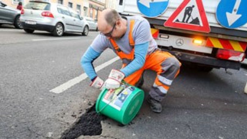 Mitarbeiter füllt ein Schlagloch auf