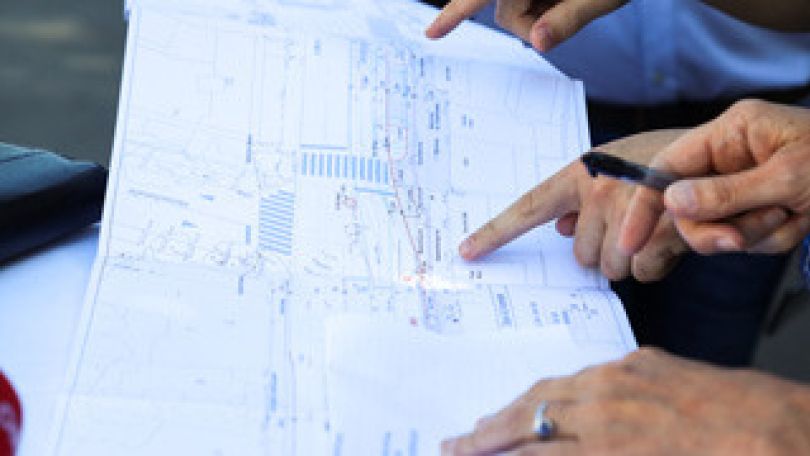 Mehrere Hände zeigen auf eine Planskizze